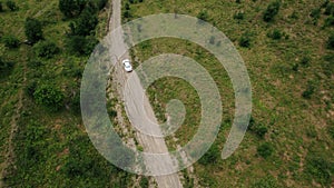 Flying above the countryside summer landscape with a driving lonely car. Action. Green nature and a narrow road with