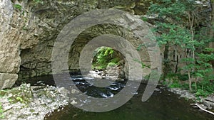 Flying Above River Running Through Beautiful Cave At Summer