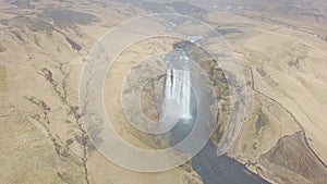 Flying Above Skogafoss Waterfall in Iceland, Water Coming From the Melting Glacier of Eyjafjallajokull Volcano. Hilly Landscape at