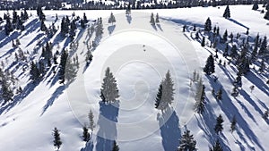 Flying above snow covered evergreen forest in the mountains. Aerial drone view of fir trees in winter