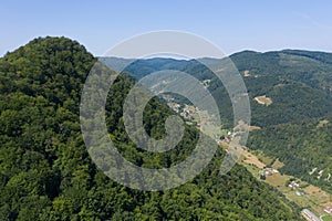 Flying above a valley and deciduous forest. Aerial shot by drone. Iada valley, Apuseni mountains, Romania