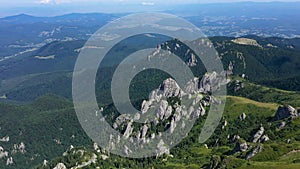 Flying above vibrant green rocky mountains and cliffs, aerial view