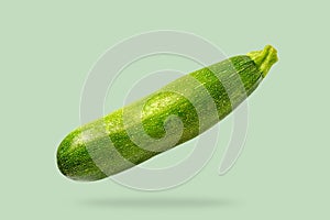 Flying in air fresh green zucchini isolated on pastel green background