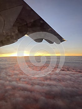 flying airplane\'s wing with an amazing sunset at the horizon sky shines its red light