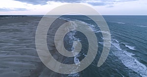 Flying along tropical beach over storm debris and water waves