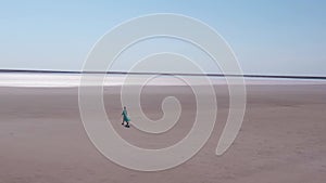 Flying around beautiful woman in long blue dress walking alone in salt dessert.