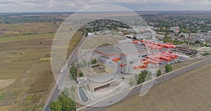 Flying around a new modern factory in orange colors. Industrial exterior of a modern factory. Modern factory top view