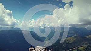 Flying backward over girl with raised hands on Piz Boe mountain top in Dolomites