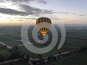 Flying Balloon over the green fields of the city of Luxor at dawn