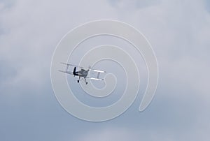 Flying biplane in the cloudy sky