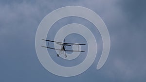 Flying biplane in the cloudy sky