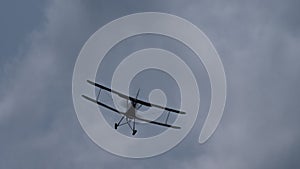 Flying biplane in the cloudy sky