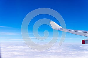 Flying into blue sky and sea of clouds and Wing of airplane with