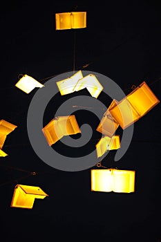 Flying books light bulbs in dark background