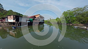 Flying close Asian village embankment boat water river local rural house green forest