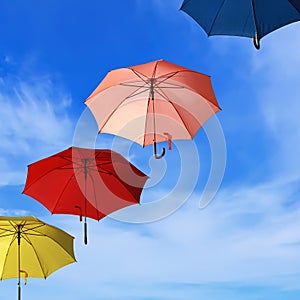 Flying colorful umbrellas blue sky background