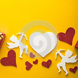 Flying cupid silhouette with hearts, happy Valentine`s Day banners, paper art style. Amour on yellow paper