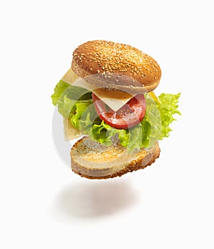 Flying deconstructed sandwich made from slices of bread, tomato, cheese and green lettuce on a white background. Levitation of a