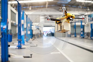 Flying delivery drone transferring parcel box from distribution warehouse to automotive garage customer service repair center