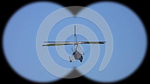 Flying deltaplan seen through binoculars. Active hobby and sport