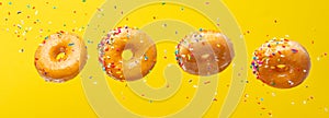 Flying donuts. A lot of donuts with colored caramel with sprinkles on a yellow background. Horizontal photo