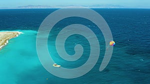 Flying a drone around man on a parachute, which is dragged by a boat near the beach, the famous resort place Rhodes