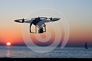 Flying drone with camera on the sky at sunset