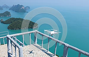 Flying Drone camera or UAV in the blue sky with ocean and island