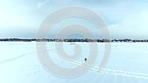 Flying with a drone mid-air towards the fort made of snow on the frozen river at Berges-des-goelands in Laval-Ouest on a cloudy