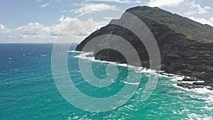 Flying drone over the ocean. View of makapuu lighthouse. Waves of Pacific Ocean wash Rocky shore. Magnificent mountains