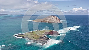 Flying drone over the ocean. View of Rabbit Island. Waves of Pacific Ocean wash over yellow sand of tropical beach