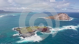 Flying drone over the ocean. View of Rabbit Island. Waves of Pacific Ocean wash over yellow sand of tropical beach