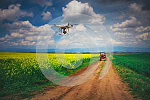 Flying drone over the rapeseed field and tractor