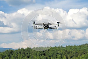 Flying drone quadcopter closeup front view with forest