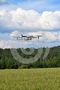 Flying drone quadcopter closeup front view with forest and field