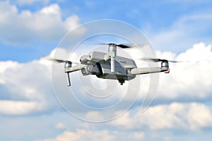 Flying drone quadcopter closeup side view with a blue sky background