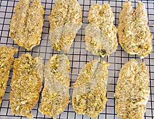 Flying fish breaded and resting on a metal rack prior to frying