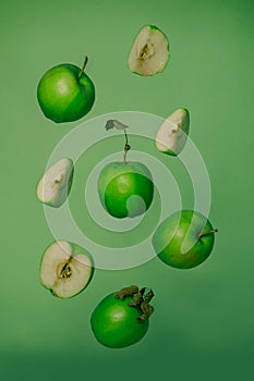 Flying fresh green apple with seeds on green background. Apple or fruits in the air