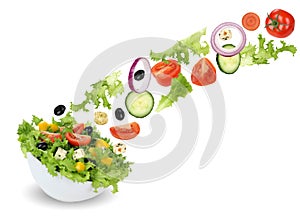 Flying green salad in bowl with tomatoes, onion, olives and cucumber