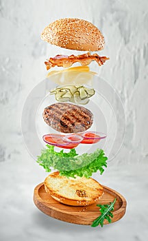 Flying hamburger on gray concrete background. Fast food concept