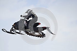 Flying high on a snowmobile rider against the sky