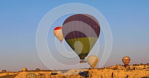 Flying hot air balloon descends to the ground over the GÃ¶reme valley in the Cappadocia district in Turkey.