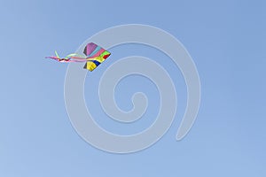 Flying kite in cloudless blue sky.
