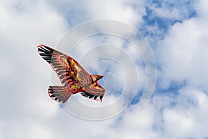 Flying kite in form of Eagle flying in blue cloudy sky