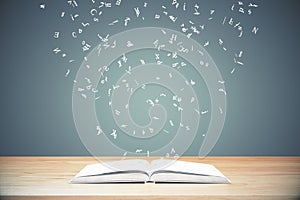 Flying letters from the opened book on wooden table