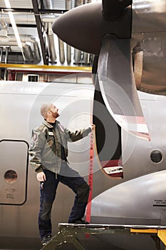 Flying machine. Full length shot of a pilot inspecting the propellor of his plane.