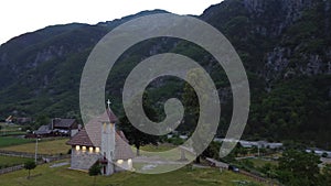 Flying near old wooden church and trees in Thethi valley, Albania. Aerial View of Theth National Park, Albanian Alps