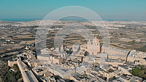 Flying over ancient town with Saint Paul Cathedral dome in Mdina old town with old buildings, top view