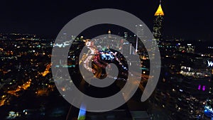 Flying over Atlanta commerial buildings. The view of nighttime downtown and freeway with traffic below. left motion