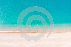 Flying over an empty sandy beach and beautiful emerald ocean waves. Top view landscape scene of waves rolling on an empty tropical